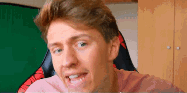 a young man is making a funny face while sitting in a chair .