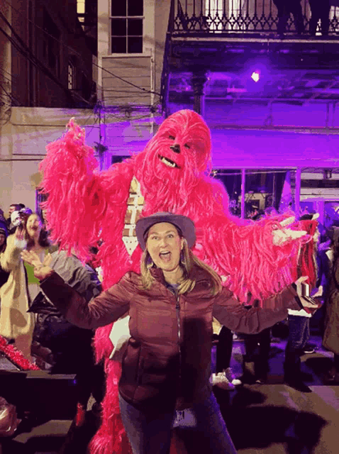 a woman in a cowboy hat is standing next to a pink chewbacca costume