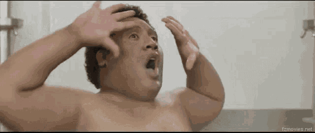 a shirtless man is taking a bath with his hands on his head ..