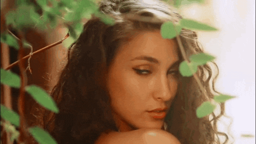 a close up of a woman 's face with leaves behind her .