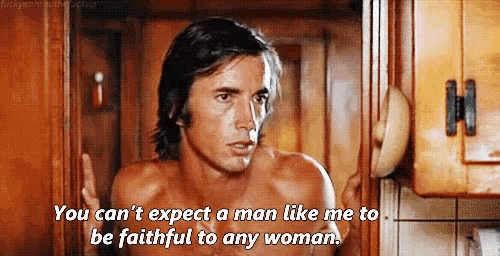 a shirtless man is talking to another shirtless man in a kitchen .