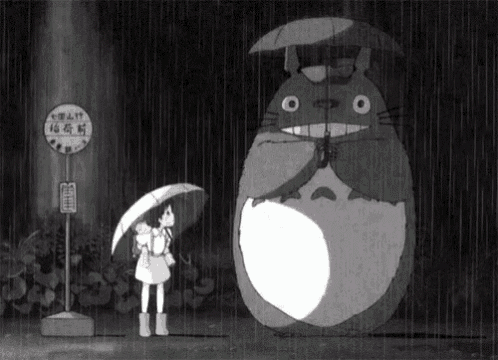 a little girl holding an umbrella standing next to a totoro