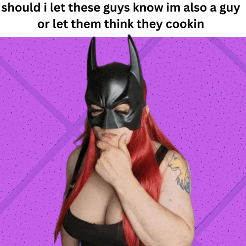 a woman with red hair is wearing a batman mask and has a tattoo on her arm