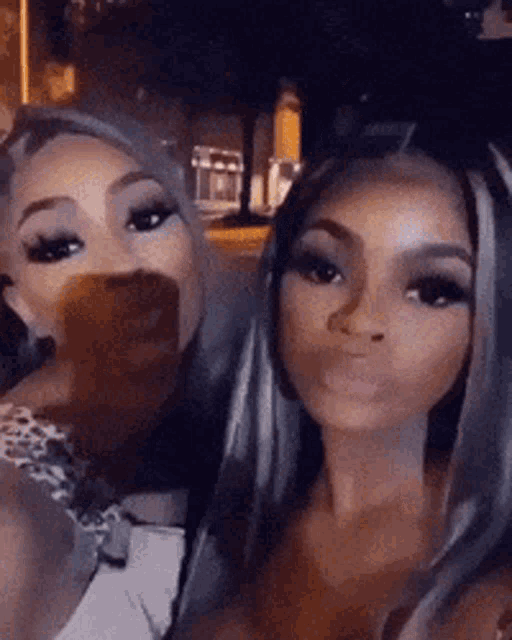 two women are posing for a picture together and one of them is covering her mouth .