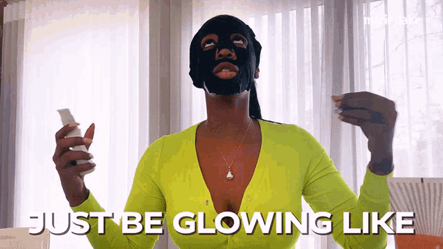 a woman with a black mask on her face is holding a bottle and saying just be glowing like