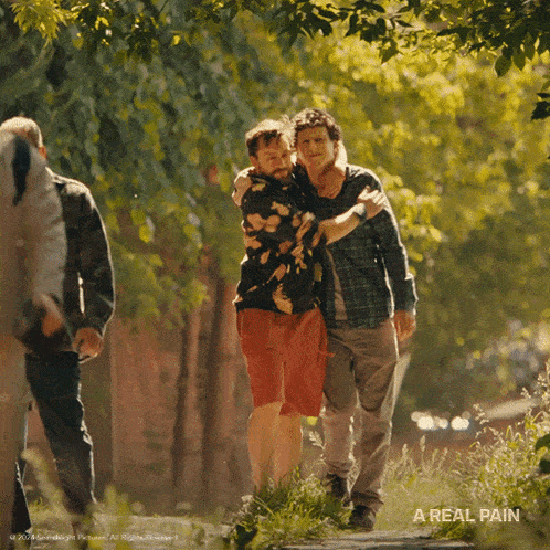 a movie poster for a real pain showing two men hugging each other