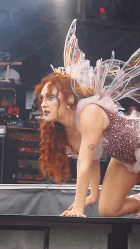 a woman in a fairy costume is kneeling down on a table