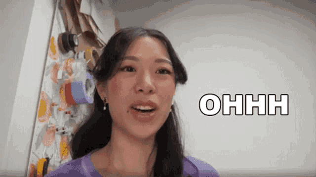 a woman in a purple shirt says ohhh in front of a wall
