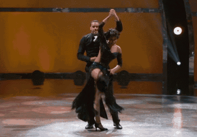 a man and a woman are dancing on a stage with a yellow background