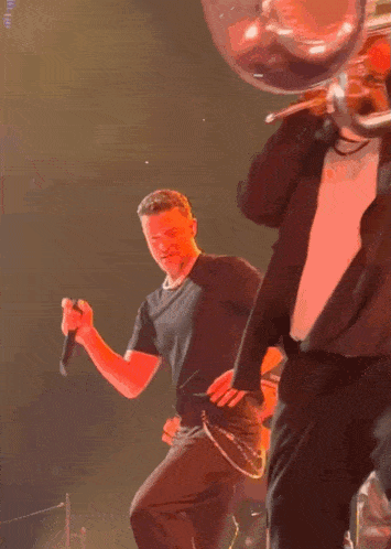 a man singing into a microphone while another man plays a trumpet