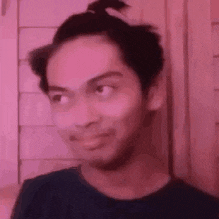 a young man with a ponytail on his head is making a funny face .