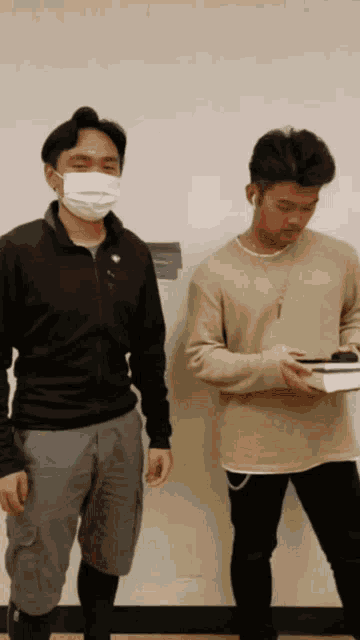 a man wearing a mask is standing next to another man