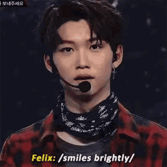 a young man wearing a bandana and a microphone is smiling brightly .