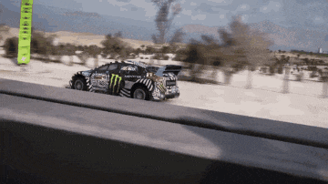 a monster energy car is driving down a dirt road