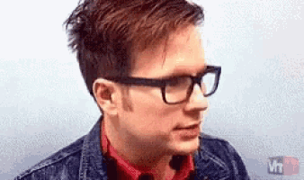 a man wearing glasses and a denim jacket is looking at something .