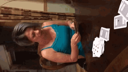 a woman in a blue tank top is playing cards