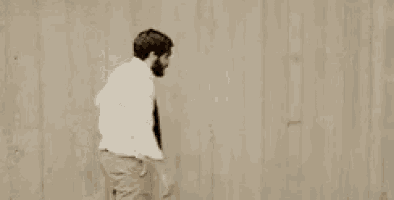 a man in a suit and tie is standing in front of a wall .