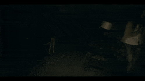 a woman in a white shirt is standing in the dark