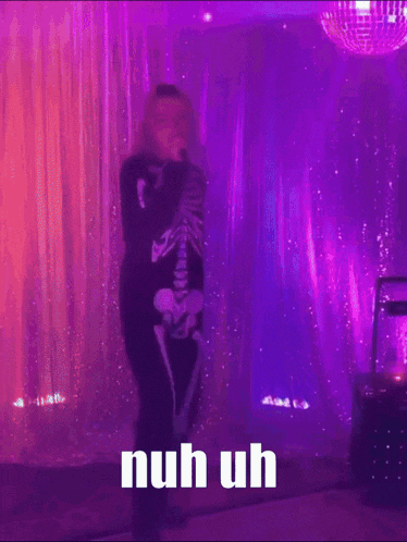 a person in a skeleton costume is singing into a microphone with the words nuh uh below them