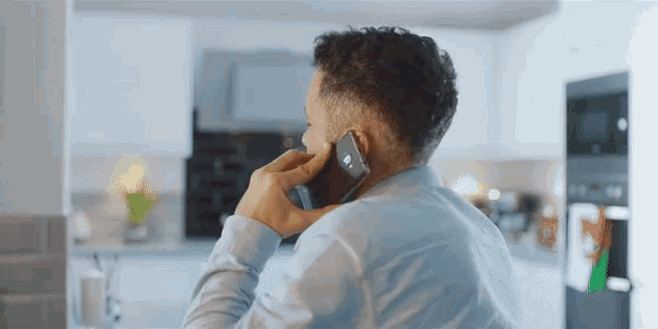 a man in a blue shirt is talking on his phone
