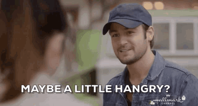 a man wearing a hat is talking to a woman and says maybe a little hungry