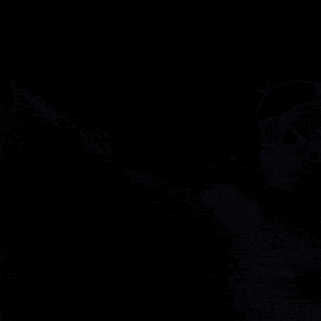 a man in a suit and tie is looking at something in a dark room .