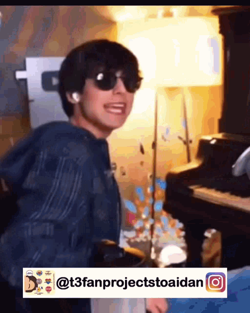 a young man wearing sunglasses is standing next to a piano