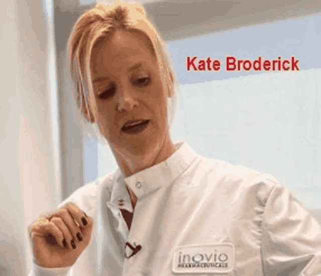 a woman wearing a white lab coat with the name kate broderick on the bottom