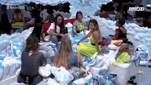 a group of women are sitting on a bed in a room with the words rede bbb on the bottom left
