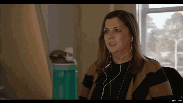 a woman wearing ear buds is sitting in front of a computer