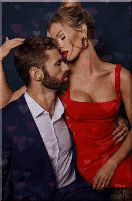 a man in a suit and a woman in a red dress are kissing with hearts surrounding them