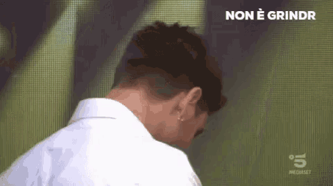 a man in a white shirt is standing in front of a screen with the words non e grindr on it .