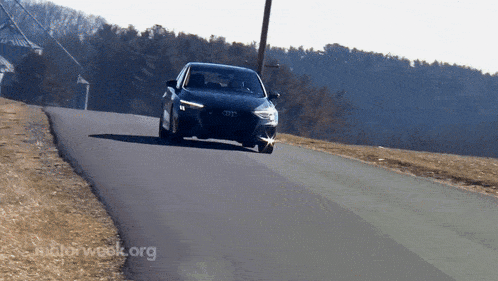 a black audi is driving down a road with motorweek.org written on the bottom