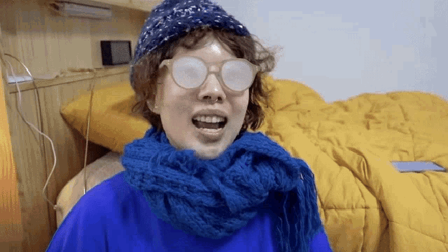 a person wearing glasses and a scarf is making a face