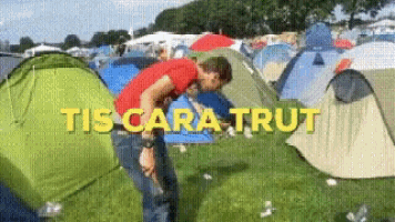 a man in a red shirt is standing in front of a tent with the words tis cara trut written on it