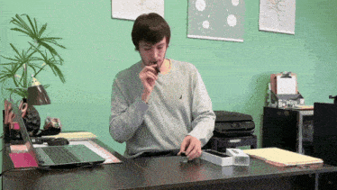 a man sits at a desk with a laptop and a bottle of liquid