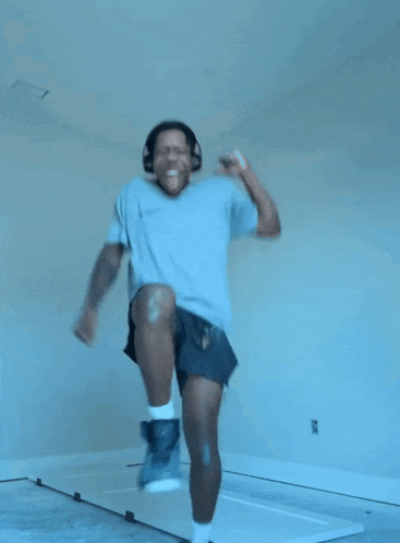 a man wearing headphones and a t-shirt that says ice is jumping in the air