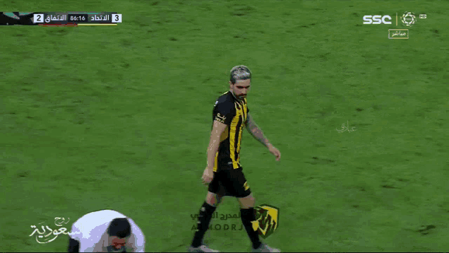 a man in a yellow and black striped shirt is walking on a field