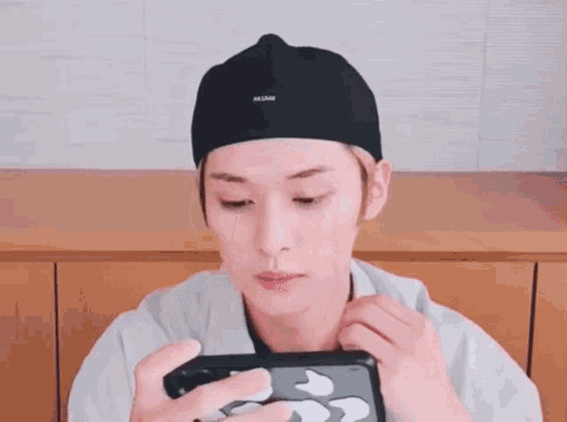 a young man wearing a hat is holding a cell phone in his hand .