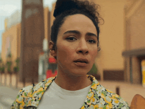 a woman with curly hair is wearing a floral jacket and a white shirt