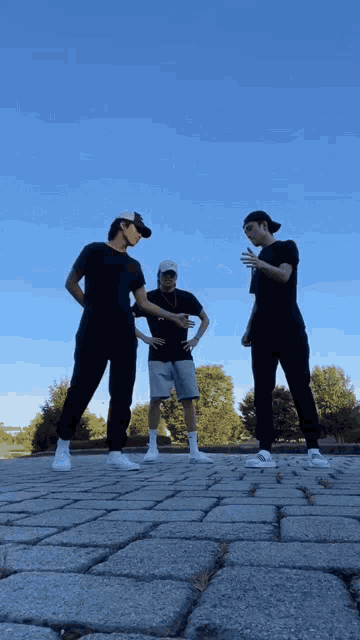 three men are standing on a brick sidewalk talking