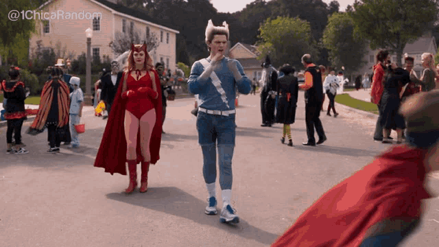 scarlet witch and quicksilver are walking down a street surrounded by people