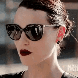 a woman is wearing sunglasses and red lipstick .