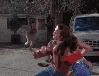 wonder woman is fighting a man in front of a white van .