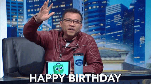a man sitting at a desk with a tablet and a happy birthday message