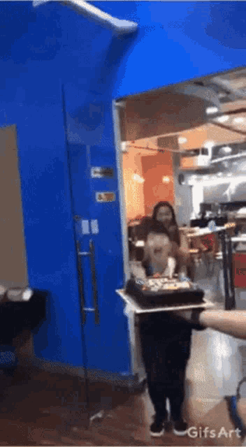 a person holding a cake in front of a glass door that says gifs art on it