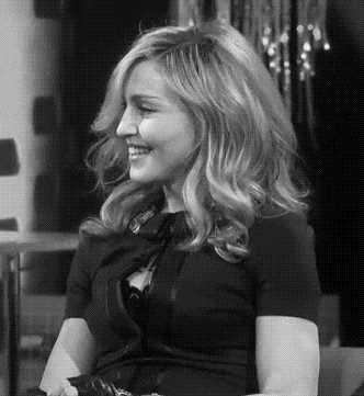 a woman is smiling in a black and white photo while wearing a black dress .