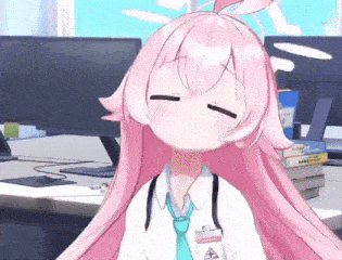 a girl with pink hair and a blue tie is sitting in front of a computer .