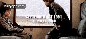 harry potter and ron weasley are sitting on a train and looking out the window .