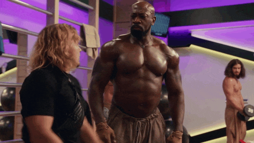 a shirtless man is standing next to another shirtless man in a gym
